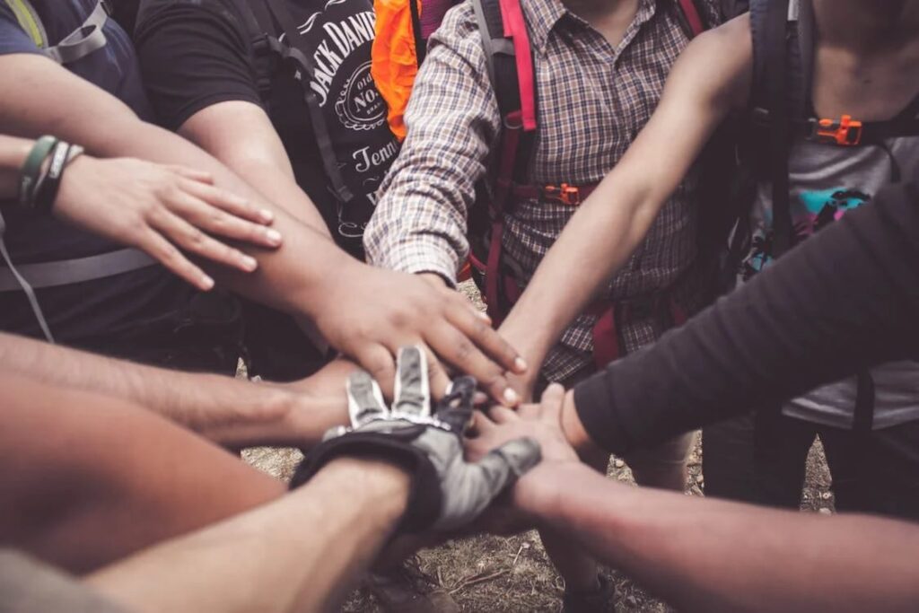 A group of people joining hands outdoors. Social Isolation and Poor Mental Health